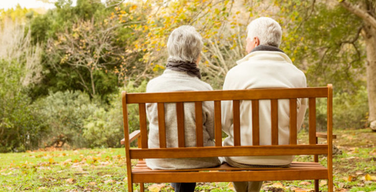 a dementia friendly garden with a bench seat with two older people sitting on it